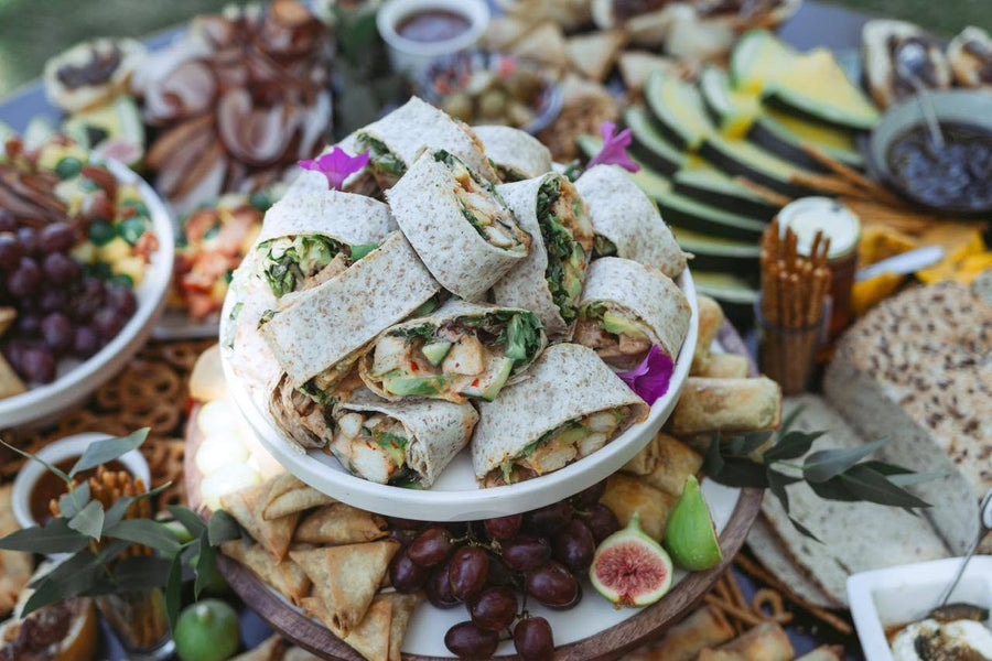 A grazing platter of cured meats, cheese and fruit, decorated with edible flowers
