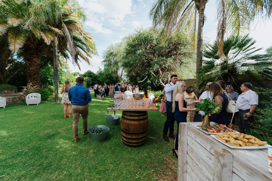 Guests mingling around wine-barrel cocktail tables on the lawn