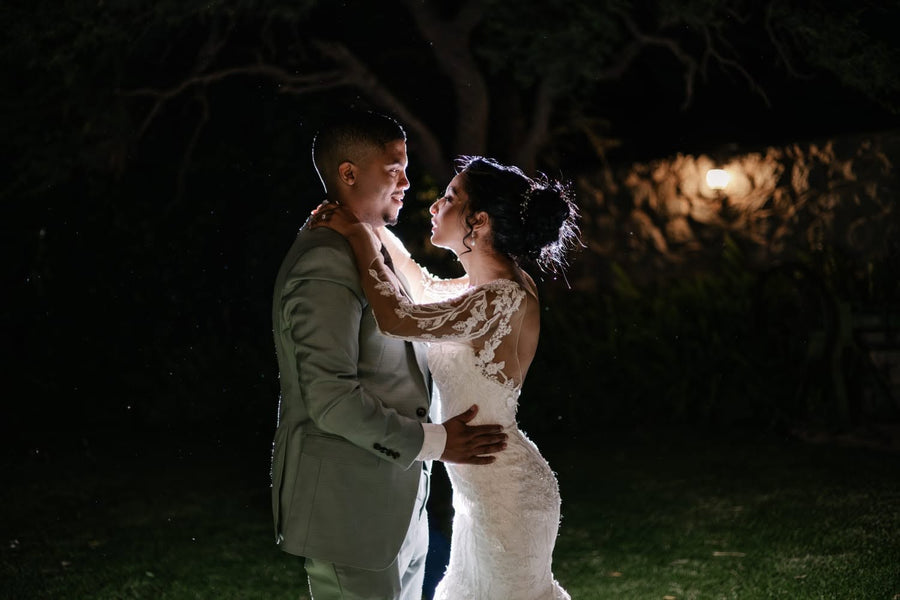 The bride and groom dancing together after dark, fairy lights glowing behind them