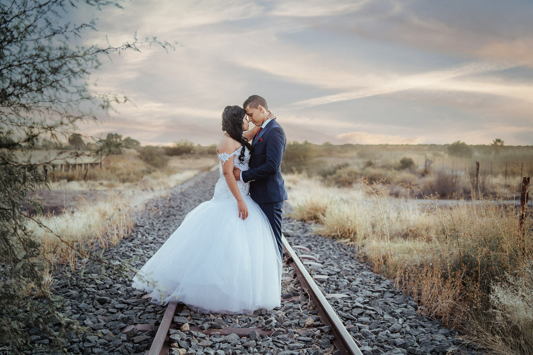 The bride and groom embracing on the railway tracks at golden hour in winter