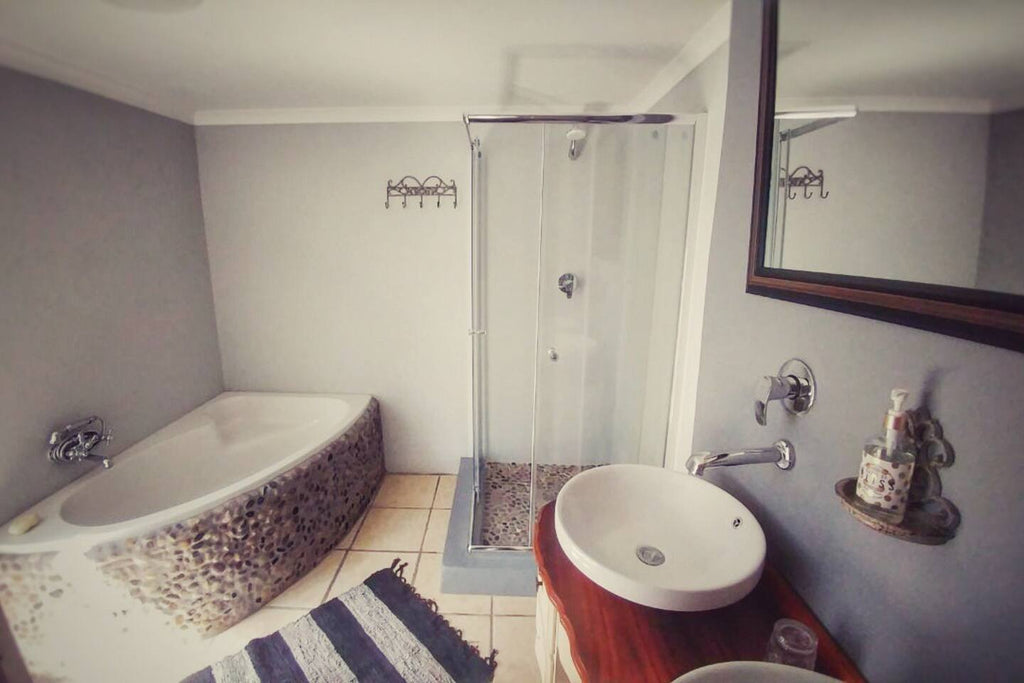 Bathroom with a bathtub, shower, sink, and mirror.