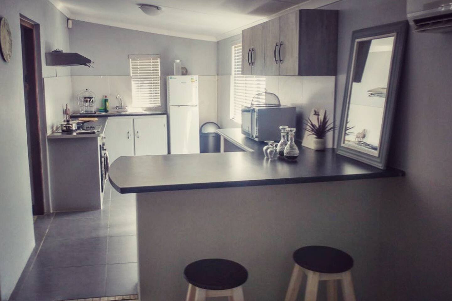 Modern kitchen with island, stools, and various appliances.