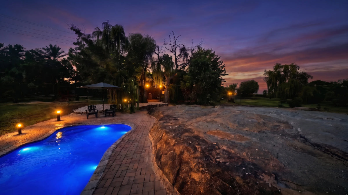The pool and granite werf at Bezalel Estate Country House, lanterns lit at dusk