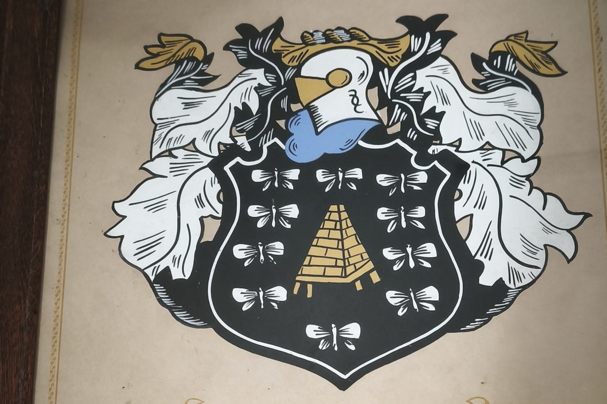The Bezuidenhout family crest, with a golden beehive on a black shield, framed on the wall at Bezalel Estate